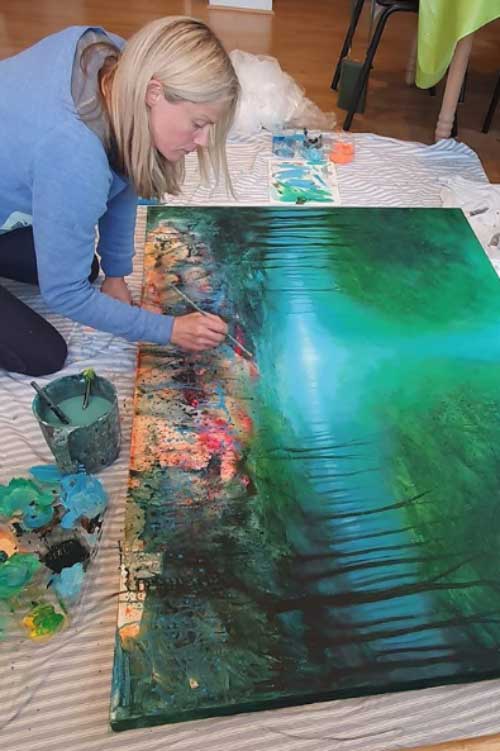 Bristol artist Jenny Urquhart in her studio, painting one of her contemporary cityscape works.