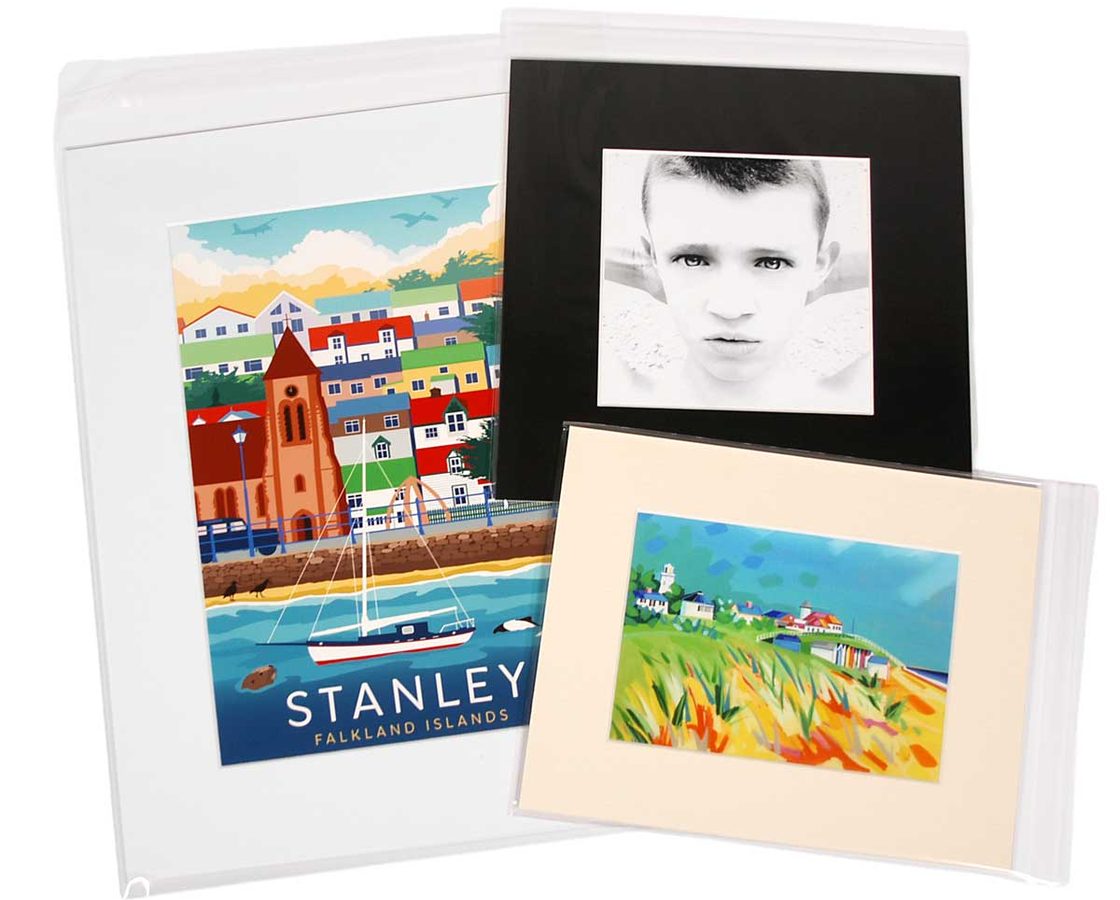 Three window-mounted fine art prints in clear cellophane sleeves — white, black, and ivory mounts